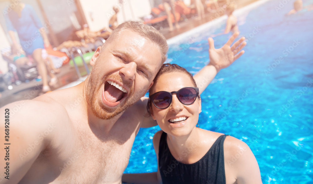 Fototapeta premium Couple happy caucasian beautiful young woman and man make selfie photo on background swimming pool. Concept travel summer trip