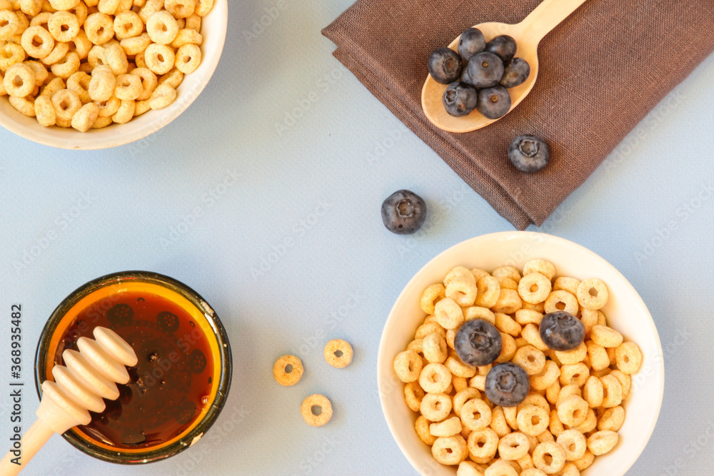 Honey rings with blueberries in a bowl on the table blue background. Copy space. Top view. Flat lay. Horizontal orientation.
