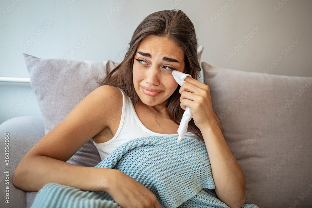 Upset woman frustrated by problem with work or relationships, sitting on couch, embracing knees, covered face in hand, feeling despair and anxiety, loneliness, having psychological trouble Upset woman frustrated by problem with work or relationships, sitting on couch, embracing knees, covered face in hand, feeling despair and anxiety, loneliness, having psychological trouble