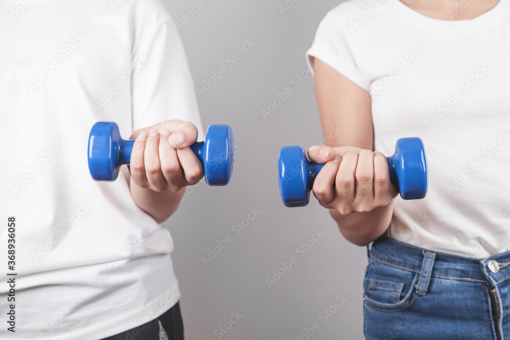 Girls holding dumbbells in gray background. Girls holding dumbbells in gray background.