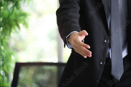 Businessman in suit giving hand for handshake with copyspace, man with open hand ready to seal a deal at workplace