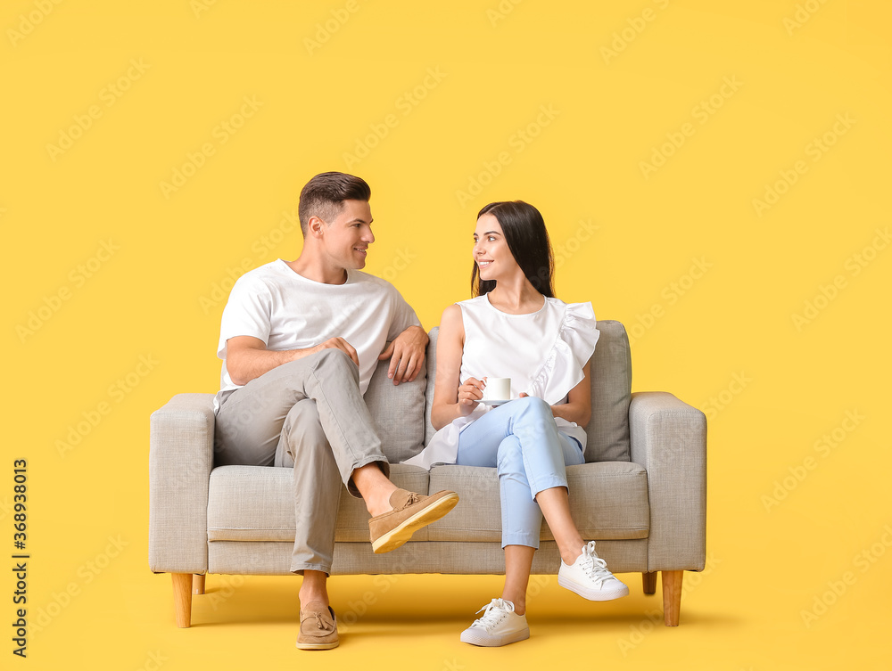 Young couple relaxing on sofa against color background Young couple relaxing on sofa against color background