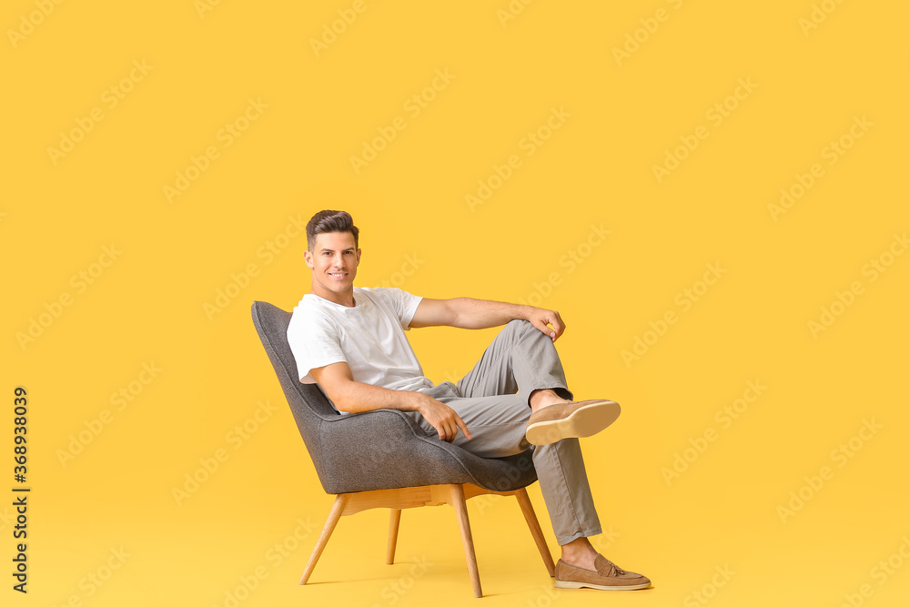 Young man relaxing in armchair against color background Young man relaxing in armchair against color background