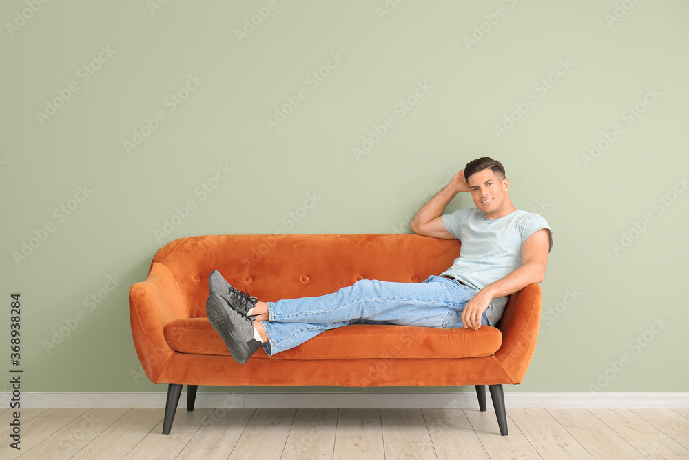 Young man relaxing on sofa near color wall Young man relaxing on sofa near color wall