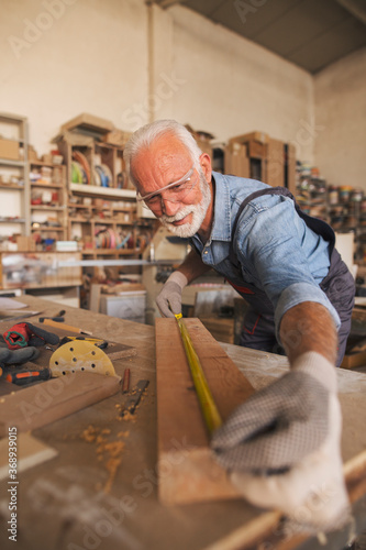 Cheerful male carpenter working with wood in his workshop