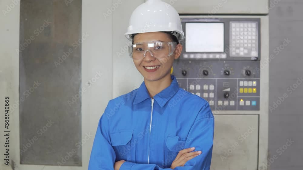 B-roll of The female technician working in the factory is standing, crossing her arms and smiling happily in his factory. Businesswoman engineering working in a factory with a lathe. Woman Working. B-roll of The female technician working in the factory is standing, crossing her arms and smiling happily in his factory. Businesswoman engineering working in a factory with a lathe. Woman Working.