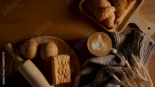 Breakfast table with freshly baked delicious bread, latte coffee and decorations on wooden table