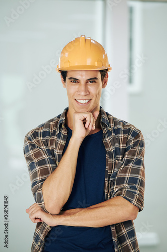 Handsome young contractor in hadrthat with toothy smile looking at camera