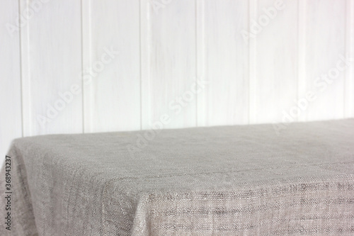 Fototapeta Naklejka Na Ścianę i Meble -  empty table with a gray linen tablecloth against a white Board wall.