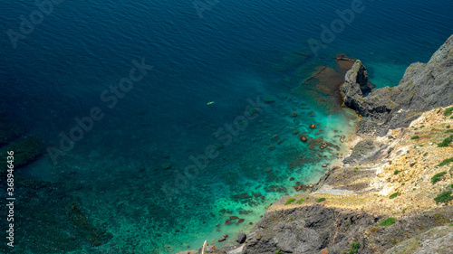 A rock peninsula overlooking the Black Sea, a boat rides into the sea, a calm turquoise blue sea against a general background.