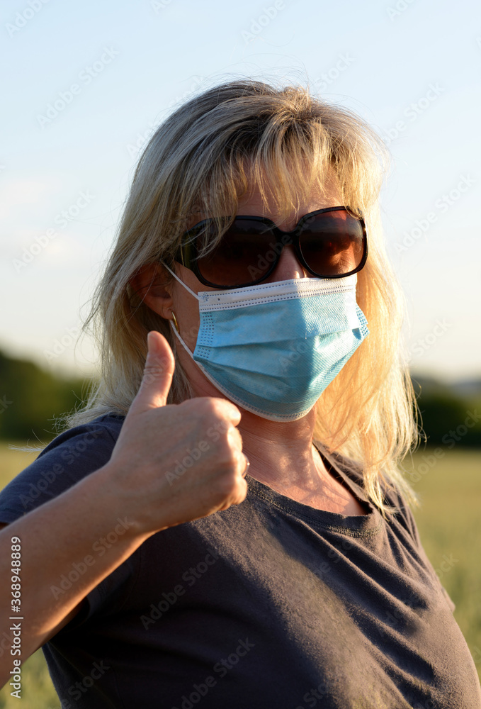 Woman in medical protective mask on her face doing thumbs up gesture. Life during covid-19 pandemic. Woman in medical protective mask on her face doing thumbs up gesture. Life during covid-19 pandemic.