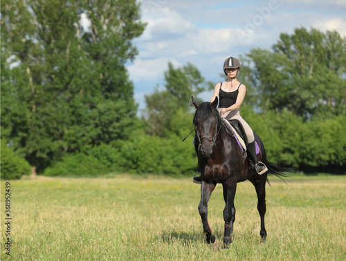 Beautiful equestrian girl ride sports dressage horse in summer forest