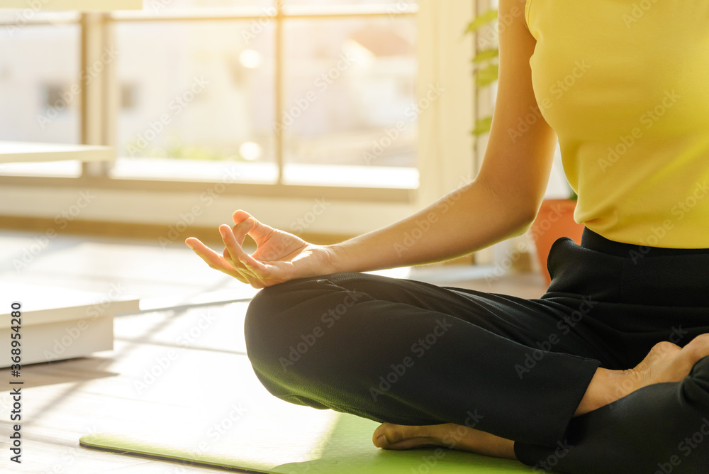 Close up to female hand while Asia woman practicing yoga lesson, breathing, meditating in living room at home. Close up to female hand while Asia woman practicing yoga lesson, breathing, meditating in living room at home.