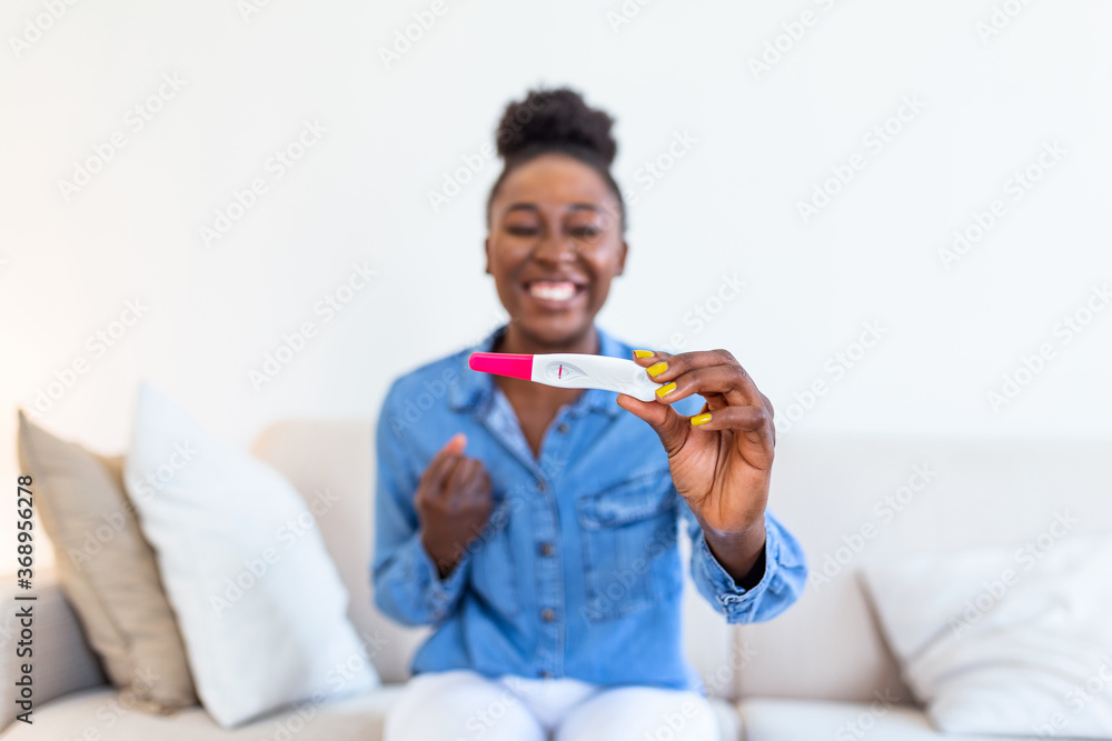Young happy woman holding positive pregnancy test, shallow depth of field. Happy that she is going to have baby. Finally pregnant. Young happy woman holding positive pregnancy test, shallow depth of field. Happy that she is going to have baby. Finally pregnant.