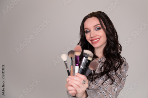 Girl makeup with brush cosmetics on a white gray background
