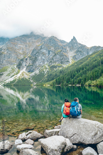 Morske Oko, Poland - September 12, 2019: hikers couple sitting on rock looking at lake in mountains