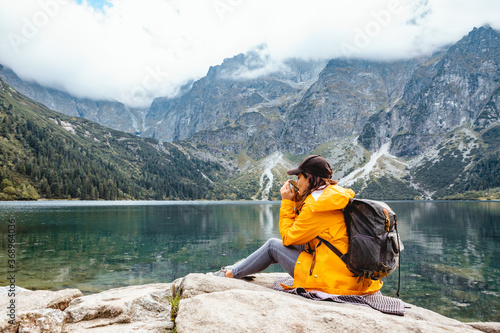 woman backpacker sitting on rock enjoying the view of lake at tatra national park mountains