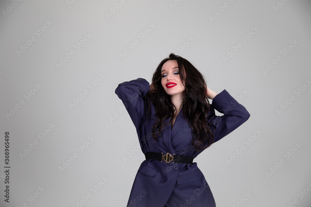 Portrait of weary young beautiful woman in oversized man's suit sitting isolated grey background Portrait of weary young beautiful woman in oversized man's suit sitting isolated grey background