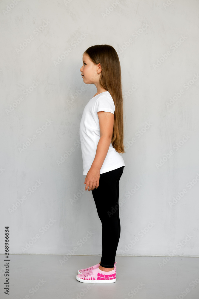 Fototapeta premium Cute young child with long hair in white t-shirt and black sweatpants