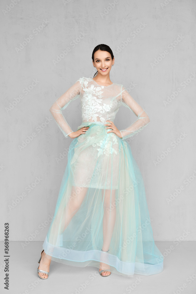Beautiful young woman plays with hem of transparent tulle dress with lace Beautiful young woman plays with hem of transparent tulle dress with lace