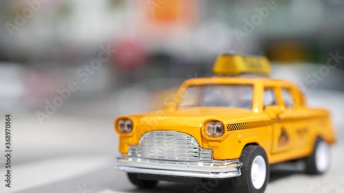 Yellow vacant mini taxi cab close up, Harmon corner, Las Vegas, USA. Small retro car model on defocused background. Little iconic auto toy as symbol of transport in soft focus. Blurred shopping mall © Dogora Sun