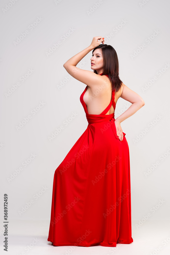 Sexy woman in red dress in studio on gray background