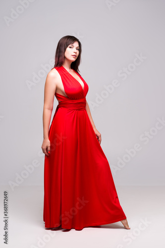 Beautiful woman in red dress in studio on gray background