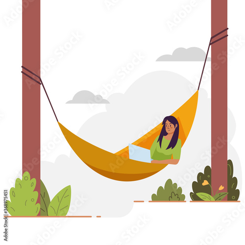 Young woman lies with laptop on hammock