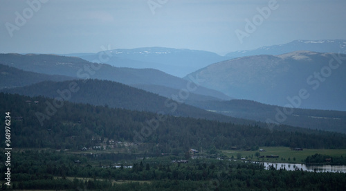 Foggy mountain layers and cabins during blue hour and sunset. Peaceful and tranquil scenery.