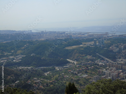 Genova, Italy – 07/30/2020: Beautiful scenic aerial view of the city, port, dam, sea, Cristoforo Colombo airport runway, containers shipping terminal, Pra, Voltri, and Sestri promontory from Monte Gaz