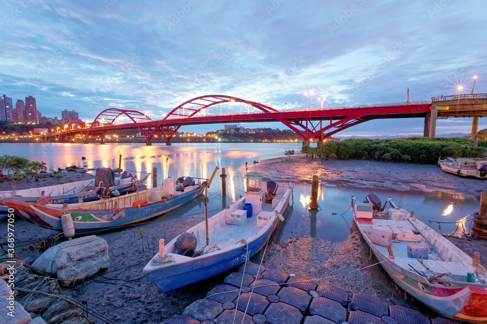 Obraz premium Early morning scenery of stranded boats by riverside during low tide and in the background, the beautiful landmark Guandu Bridge spanning across Tamsui River in Taipei, Taiwan, Asia