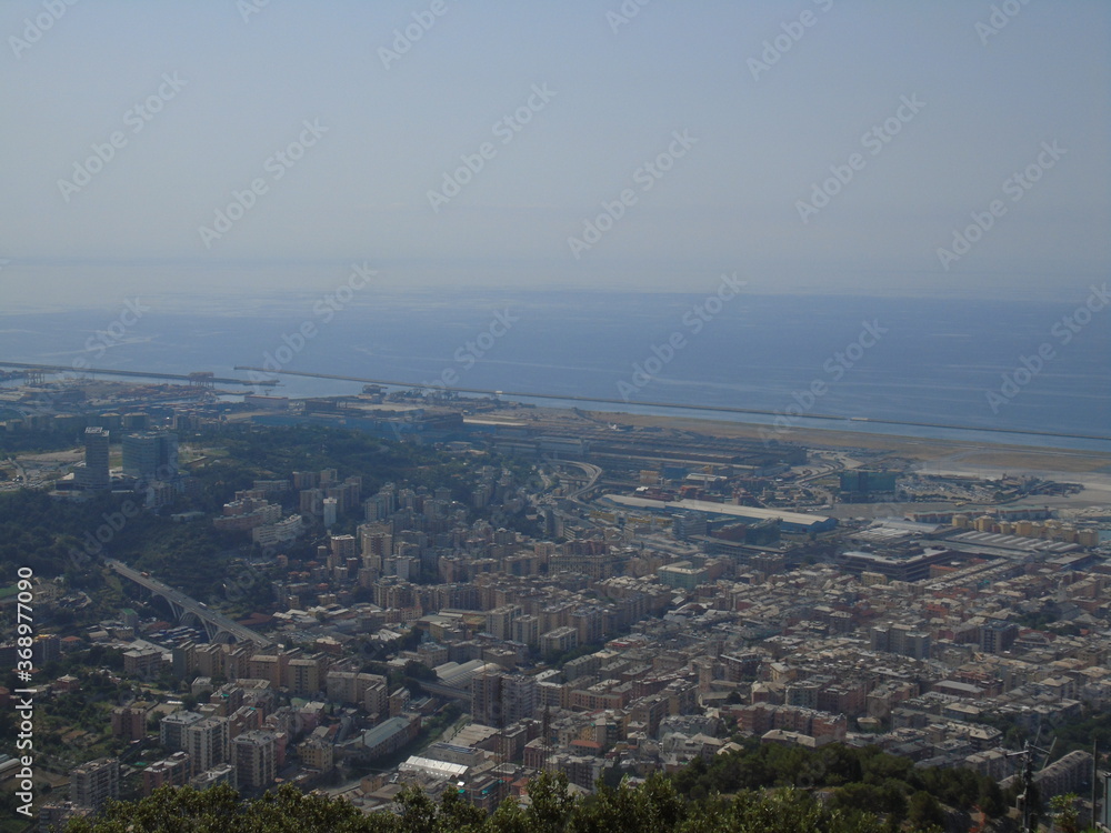 Genova, Italy – 07/30/2020: Beautiful scenic aerial view of the city, port, dam, sea, Cristoforo Colombo airport runway, containers shipping terminal, Pra, Voltri, and Sestri promontory from Monte Gaz