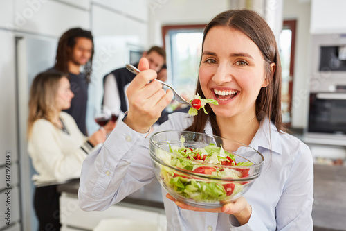 Young woman eating salad in shared kitchen