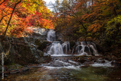 Beautiful autumn waterfall red and yellow colorful tree leaves with stream of mountain.  C