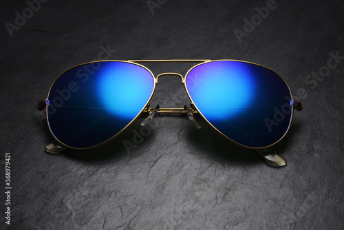 Blue mirror aviator sunglasses on black slate background