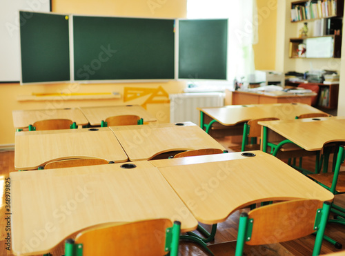 an empty schoolroom without people, a green blackboard and wooden desks with chairs-preparation for the lesson, back to school, education, Knowledge Day. Modern school interior. photo