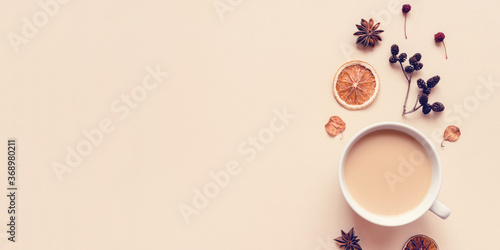 Autumn pastel background. A cup of hot coffee or tea with milk with autumn leaves and anise. Banner with copy space for text. Flat lay, top view.