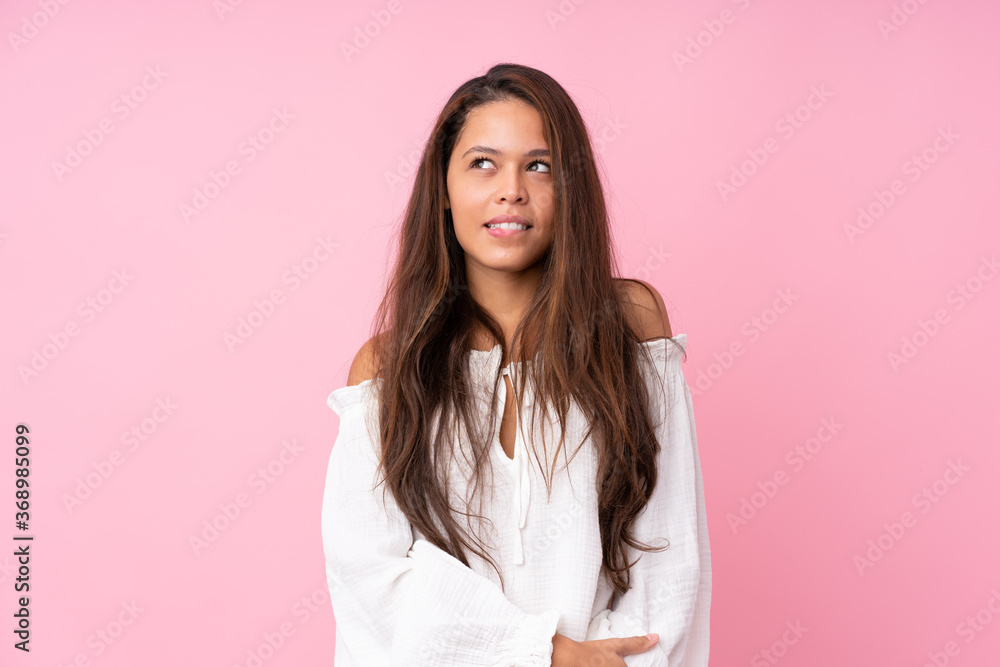 Young Brazilian girl over isolated pink background with confuse face expression