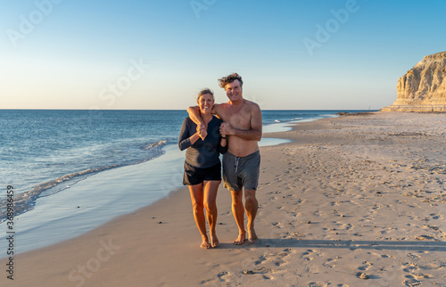 Happy active and healthy mature couple walking on the beach enjoying outdoors lifestyle
