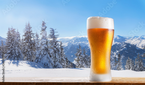 cold glass of beer on a wooden table against winter landscape