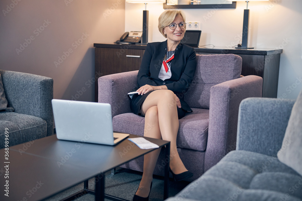 Beautiful businesswoman sitting in armchair in hotel room Beautiful businesswoman sitting in armchair in hotel room
