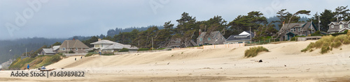 Panoramic view of the cozy houses on the ocean shore in the Cannon Beach city on a misty day. © thecolorpixels