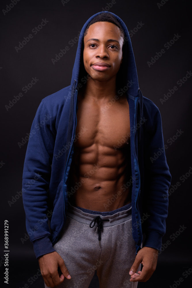 Fototapeta premium Young handsome African man against black background