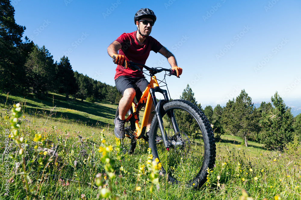 Naklejka premium man riding his mountain bike in a meadow