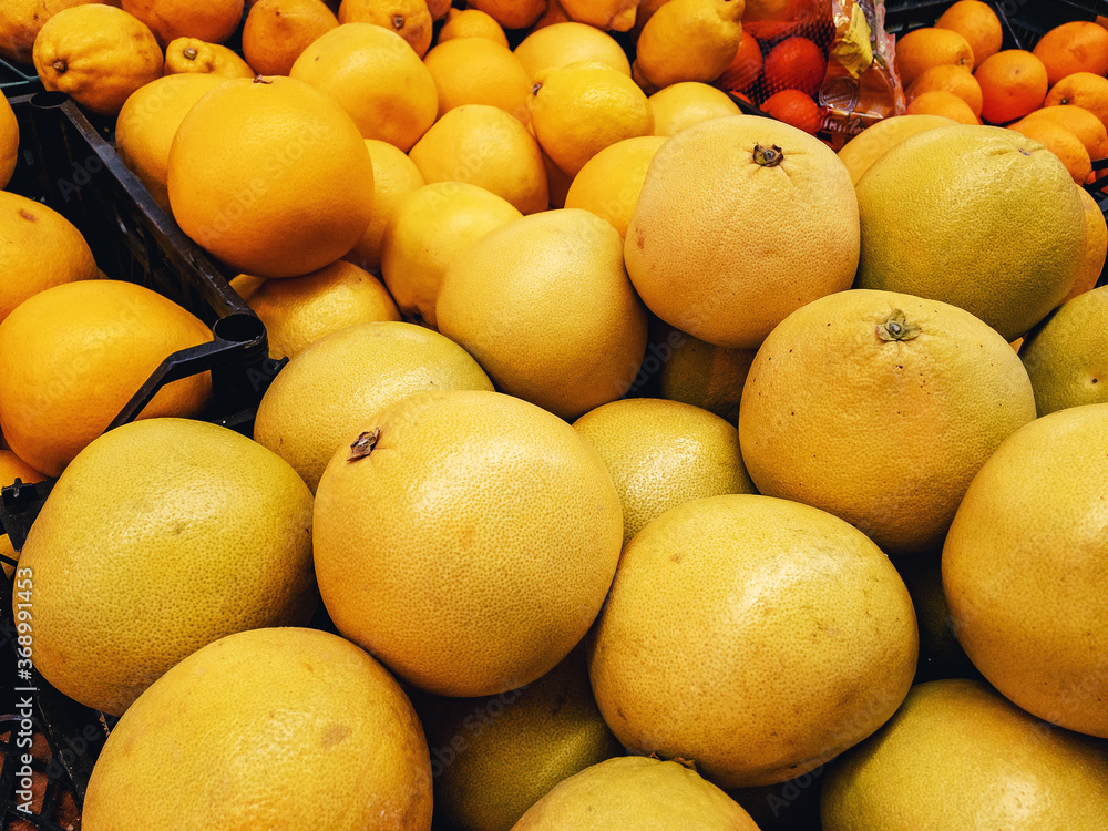 Large ripe yellow fruits of the Pomelo (Latin Citrus māxima) lie in a heap on top of each other.