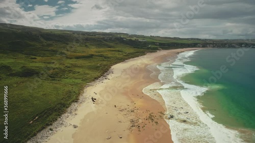 Wallpaper Mural Aerial coast beach: Atlantic Ocean, Antrim county, Northern Ireland. People walking on sandy white shore with tranquil coastal wavy water. Cloudy summer scenery. Footage shot view in 4K,UHD Torontodigital.ca