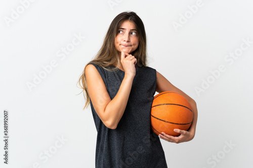 Young woman playing basketball isolated on white background having doubts and thinking © luismolinero