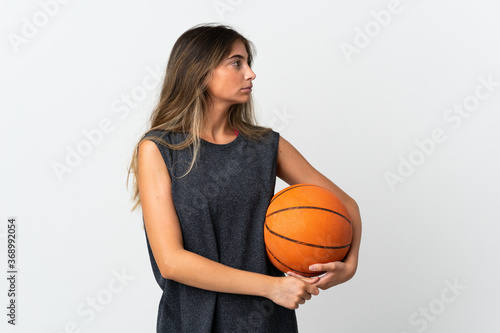 Young woman playing basketball isolated on white background looking to the side © luismolinero