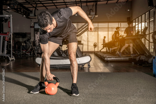 Sporty young man training with kettlebell in gym