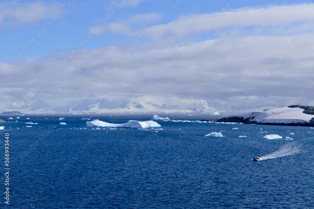 Rubber boat in antarctic landscape with blue water, iceberg, glacier, Antarctica